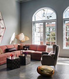 a living room filled with lots of furniture next to two large arched windows and floor lamps