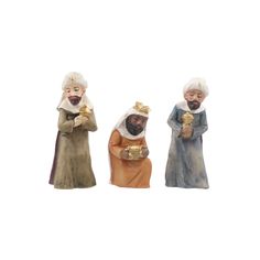 three figurines of people holding items in their hands and wearing robes, all standing side by side