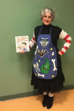 a woman in an apron holding up a book