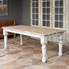 an old wooden table sitting on top of a hard wood floor next to a window