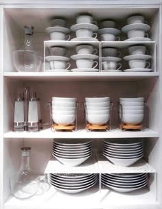 white dishes and cups are stacked on the shelves