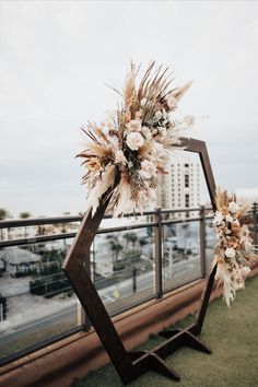 a wedding arch decorated with dried flowers and pamodia in front of a cityscape