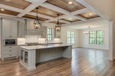 a large kitchen with an island and wooden floors in front of two windows on the wall