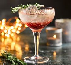 a drink in a wine glass with rosemary garnish