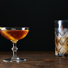 two glasses filled with liquid sitting on top of a wooden table