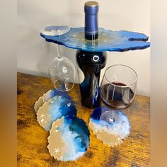 two wine glasses and a bottle sitting on a table next to some coasters that are shaped like seashells