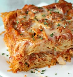 a white plate topped with lasagna casserole covered in sauce and cheese