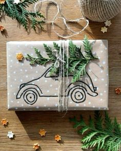 a wrapped present sitting on top of a wooden table next to christmas tree branches and decorations