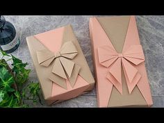 two boxes that have bows on them sitting next to each other, one is pink and the other is brown