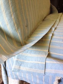 an upholstered couch with blue and white stripped fabric on it's back