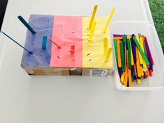 a box filled with different colored sticks on top of a white table next to a plastic container