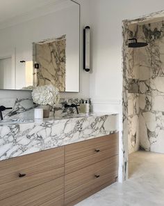 a bathroom with marble counter tops and white walls, along with large mirrors on the wall