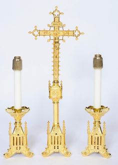 two golden candlesticks with an ornate cross on each one and a candle holder in the middle