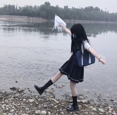 a girl is standing on the shore with her arm in the air while holding something