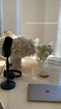 a laptop computer sitting on top of a table next to a vase with white flowers