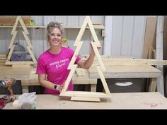 a woman in pink shirt standing next to two wooden structures with woodworking tools on them