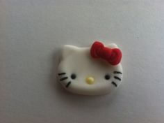 a white hello kitty brooch with a red bow on it's back end