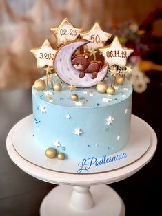 a blue cake with gold stars and a teddy bear on top