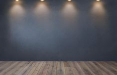 an empty room with five lights on the wall and wood flooring in front of it