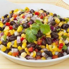 a white bowl filled with black beans, corn and cilantro