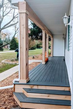 a porch with steps leading up to the front door and an orange vase sitting on top of it