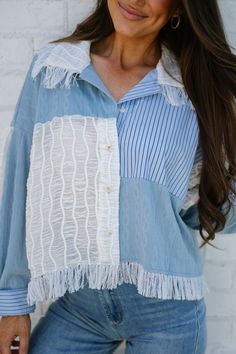 a woman wearing a blue and white shirt with fringes