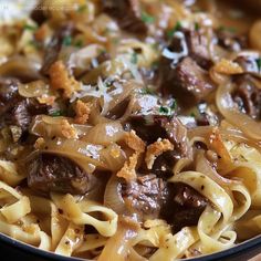 a close up of a plate of food with noodles and meat in sauce on it