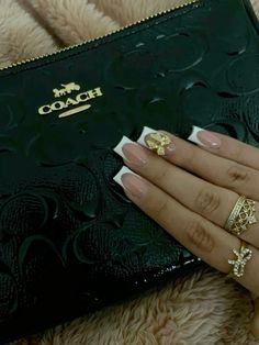 a woman's hand with two gold rings on her fingers and a black purse