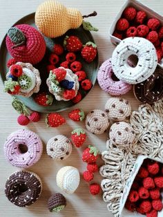 crocheted donuts, raspberries and other items are arranged on a table