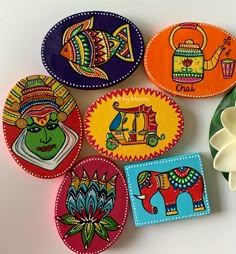 four colorful coasters with designs on them next to a white flower and green plant