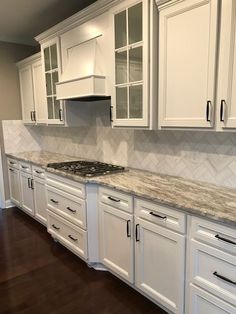 a kitchen with white cabinets and marble counter tops