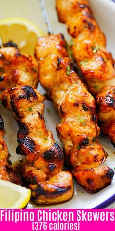 chicken skewers on a plate with lemon wedges