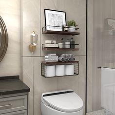 a white toilet sitting in a bathroom next to a wall mounted shelf filled with towels