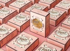 many boxes of rose soap on a pink surface with the words rose written in gold