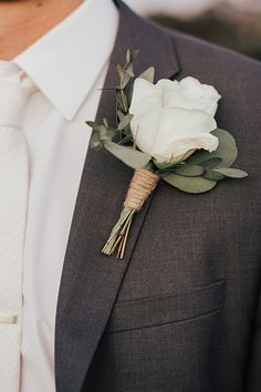 a man in a suit with a boutonniere and white rose on his lapel