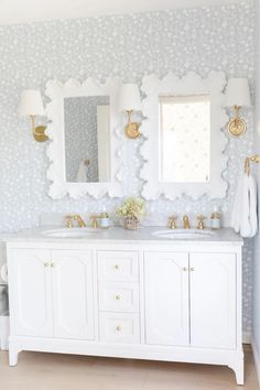 a bathroom with two sinks, mirrors and lights on the wall above them is shown