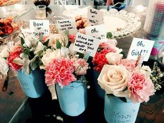 three blue vases with flowers and signs on them