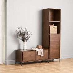 a wooden cabinet sitting on top of a hard wood floor next to a white vase