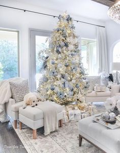 a living room decorated for christmas with a white tree in the middle and silver decorations on the walls