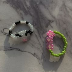 two bracelets sitting next to each other on a marble counter top, one is green and the other is pink