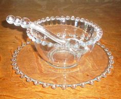 a glass bowl with beaded handles on a wooden table