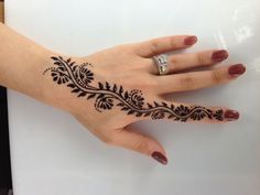 a woman's hand with black henna tattoo on her left arm and wrist