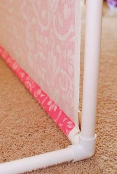 a close up of a white pole on the ground with a pink wallpaper behind it