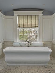 a large white bath tub sitting under a window