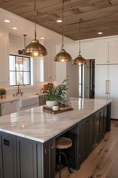 a large kitchen with an island and two pendant lights hanging from it's ceiling