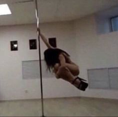 a woman is hanging upside down on a pole in an empty room with no one around