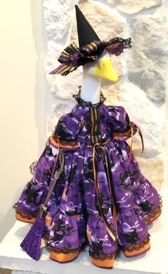 a purple and orange dress with a black hat on top of it's head