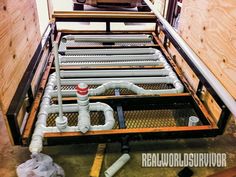 pipes are connected to the back of a bed frame in an unfinished room with wood paneling