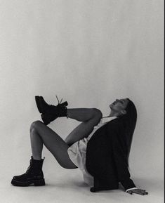 a black and white photo of a woman laying on the ground with her legs crossed