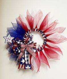 a red, white and blue wreath with stars on the top is hanging on a wall